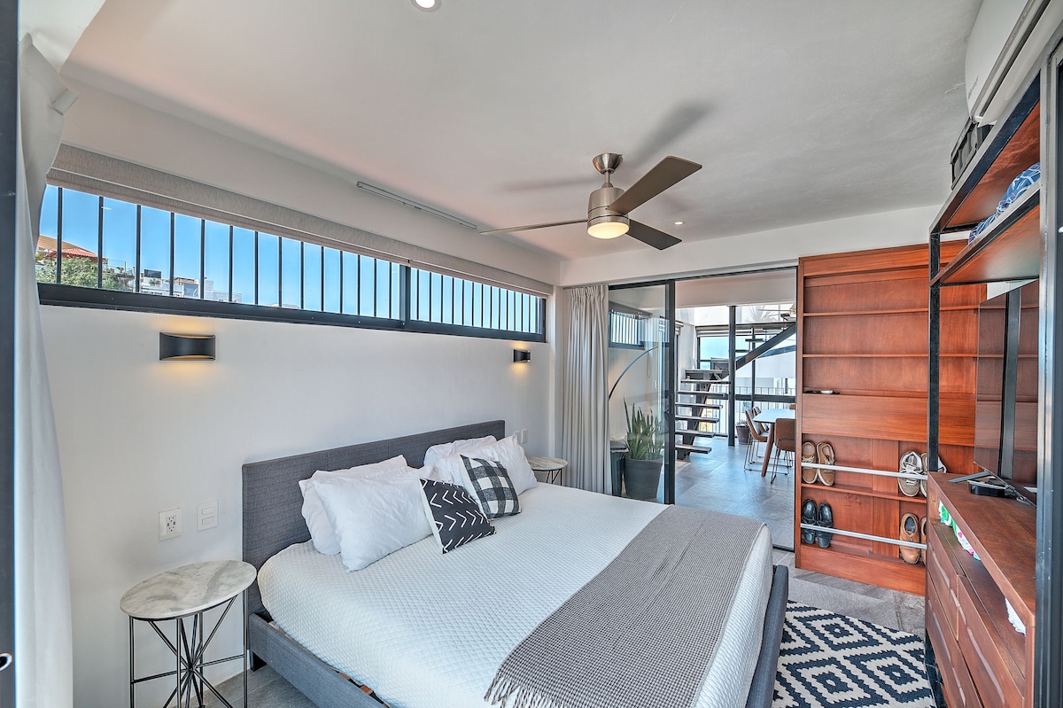 King bedroom with wooden doors, ceiling fan and large windows